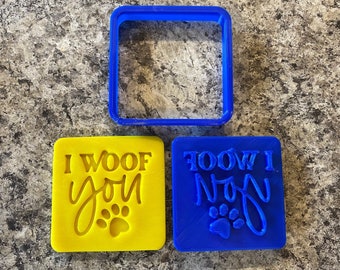 May include: Two blue and yellow plastic cookie cutters with the text "I woof you" and "Woof I you" with a paw print design.