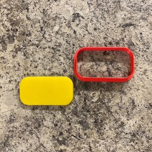 May include: A yellow rectangle cookie cutter and a red rectangle cookie cutter.