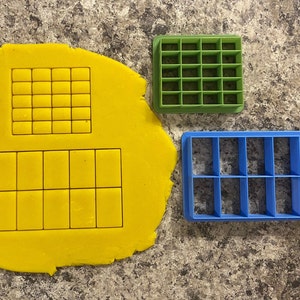 Może przedstawiać: Trzy foremki do ciasteczek, jedna zielona, jedna niebieska i jedna odciśnięta na żółtym cieście. Zielona foremka ma kratkę z 20 kwadratów. Niebieska foremka ma kratkę z 12 kwadratów. Ciasto ma odciśnięte dwie kratki, jedną z 16 kwadratów i jedną z 12 kwadratów.