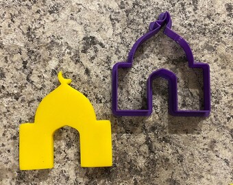 May include: Two cookie cutters shaped like mosques. One is purple and the other is yellow.