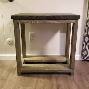 May include: A wooden console table with a dark stained top and a gray-stained frame. The table has a lower shelf and is approximately 30 inches tall, 36 inches wide, and 12 inches deep.