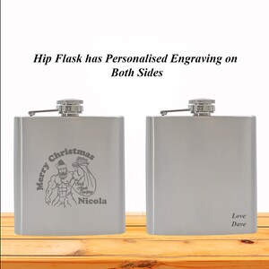 May include: Silver hip flask with a personalised engraving on both sides. One side features a cartoon of a muscular Santa Claus with the text "Merry Christmas" and "Nicola". The other side has the text "Love Dave".
