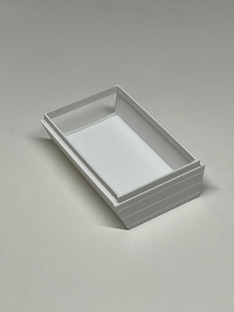 Peut inclure: Bo&icirc;te rectangulaire blanche avec un rebord sur&eacute;lev&eacute; autour du bord sup&eacute;rieur. La bo&icirc;te est en plastique blanc lisse.