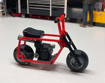 May include: A red and black miniature motorcycle with a black seat and knobby tires.