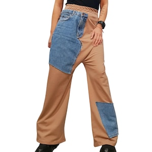 Peut inclure: Pantalon large de couleur beige uni avec un empiècement en jean bleu contrastant sur la cuisse droite et une petite pièce en jean bleu sur le bas de la jambe gauche. Le pantalon présente une taille haute avec une braguette zippée visible.