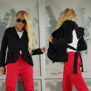 May include: A two-panel image shows a person wearing a black jacket, red pants, a white top, and black platform boots with white laces. The jacket has three buttons and pockets. The boots have a white splatter design.