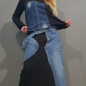 Può includere: Un completo nero composto da top a maniche lunghe e gonna con dettagli in denim. Il top presenta un pannello in denim e la gonna incorpora toppe in denim. L'outfit è completato da scarpe con plateau nere.