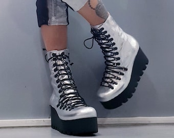 May include: Silver platform boots with black laces. The boots have a chunky platform sole and a pointed toe.