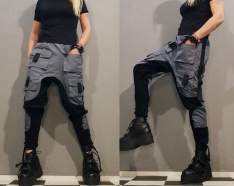 May include: Gray cargo pants with black accents and a unique design. The pants have multiple pockets and a loose fit.