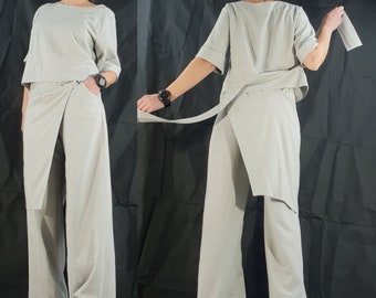 May include: A light grey two-piece outfit with a wrap-style skirt and a short-sleeved top. The top has a relaxed fit and a slightly cropped hem. The skirt has a wide leg and a long, flowing silhouette.