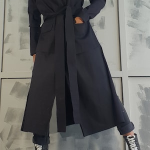 May include: A long black coat with a wide belt and pockets. The coat is made of a soft, lightweight fabric and has a relaxed fit.