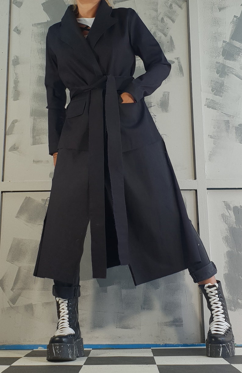 May include: A long black coat with a wide belt and pockets. The coat is made of a soft, lightweight fabric and has a relaxed fit.