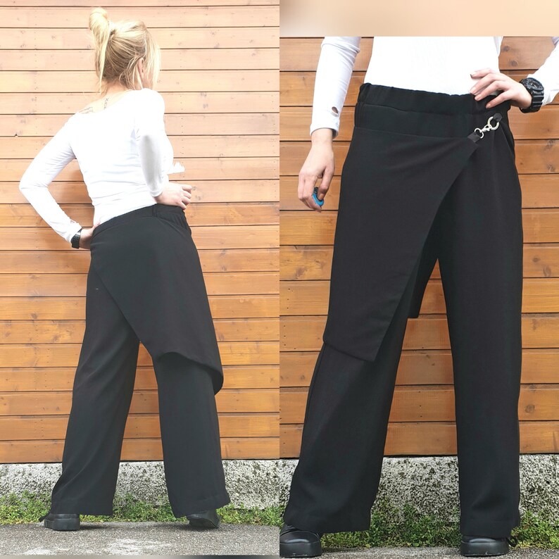 May include: Black wide-leg pants with an asymmetrical wrap design. The pants feature a high waist and a metal ring detail. The fabric appears to be a smooth, solid black material. The pants are shown from multiple angles.