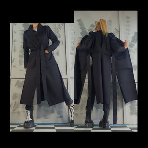 May include: A black long coat with a wide belt and a long, flowing skirt. The coat is shown from the front and back.