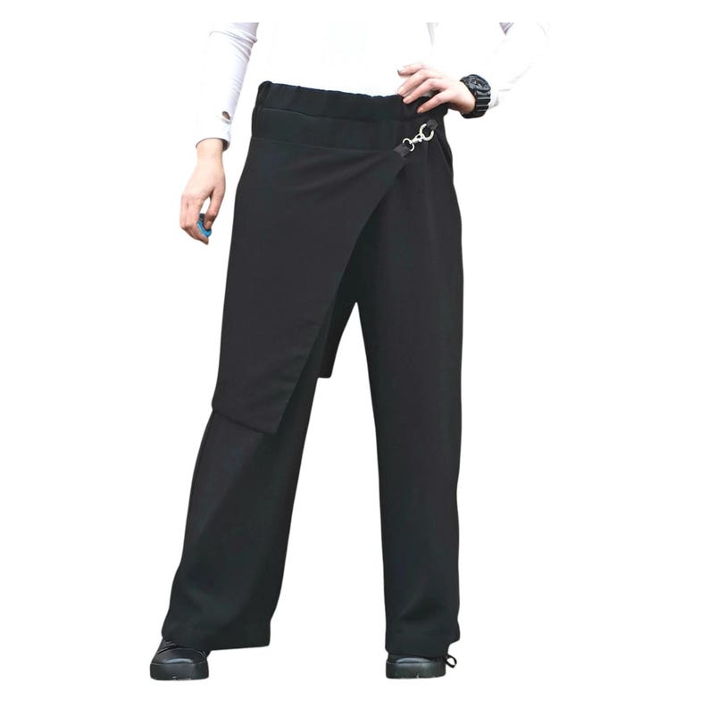 May include: Black wrap-style pants with a unique asymmetrical design. The pants feature a wide leg and a wrap-around panel secured with a silver-tone clasp. The waistline is high, and the pants are made of a solid, dark fabric.
