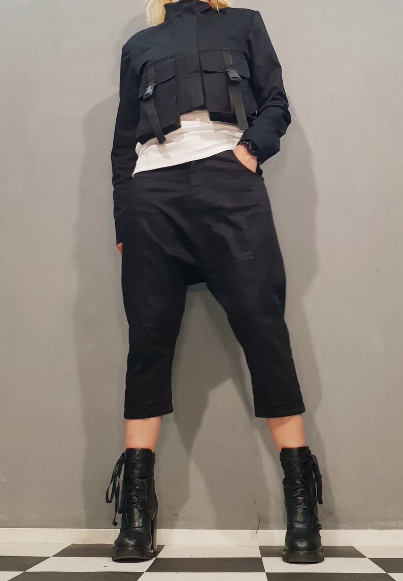 May include: A black cropped jacket with multiple straps and pockets, paired with black cropped pants and black heeled boots.
