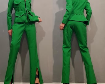 May include: A green pantsuit with a long-sleeved jacket and wide-leg trousers. The jacket has a zip fastening and a flap pocket on the chest. The trousers have a slit on each side of the leg.