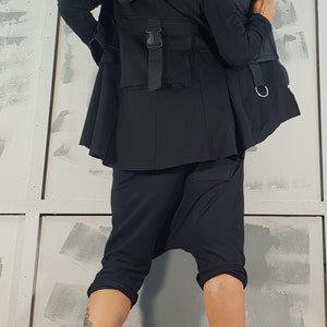 May include: A black hooded jacket with a zipper closure and a belt. The jacket has a quilted lining and a large pocket on the back. The model is wearing black pants and black boots.