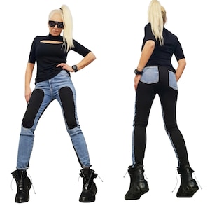 Könnte beinhalten: Ein schwarzes kurzärmeliges Oberteil mit Schlüsselloch-Ausschnitt und eine blaue Jeans mit schwarzen Einsätzen. Das Model trägt schwarze Stiefel und eine Sonnenbrille. Das Outfit ist ein moderner, kantiger Stil.