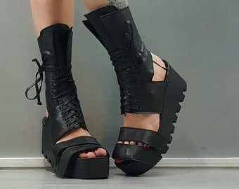 May include: Black leather platform sandals with lace-up detail and a chunky platform sole.