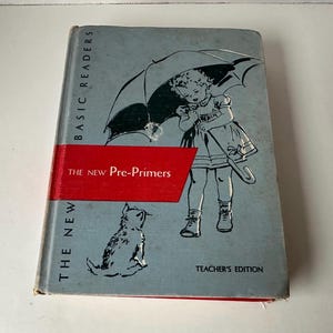 May include: Vintage "The New Pre-Primers" book. The cover features a child with an umbrella and a cat illustration. The book has a red band across the middle with the title. The book is labeled "Basic Readers" and "Teacher's Edition".