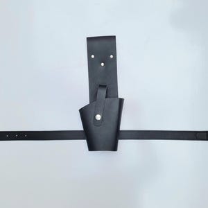 May include: A black leather belt with a holster attached. The holster has a flap that can be secured with a snap.