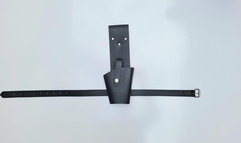 May include: A black leather belt with a holster attached. The holster has a flap that can be secured with a snap.