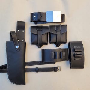 Pu&ograve; includere: Un set di accessori in pelle nera per cosplay o costumi. Il set include una cintura, due tasche, un porta-pistola per coscia e due cinturini per le gambe.
