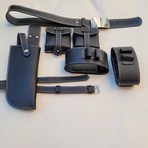 Pu&ograve; includere: Una cintura in pelle nera con fibbia argentata e pi&ugrave; tasche e cinturini. La cintura &egrave; decorata con cuciture bianche.