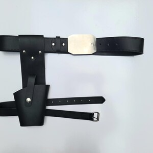 May include: A black leather belt with a silver buckle and a holster attached. The holster has a flap that can be closed with a snap.