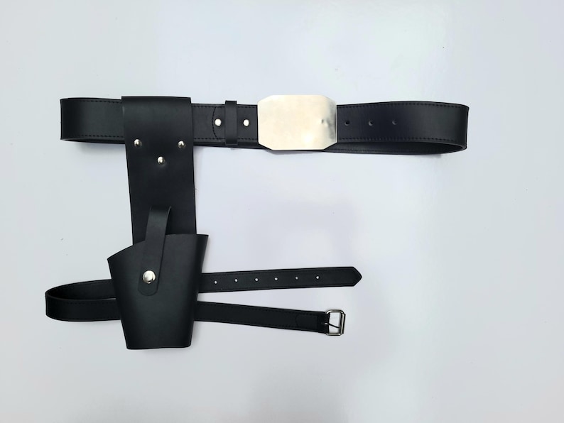 May include: A black leather belt with a silver buckle and a holster attached. The holster has a flap that can be closed with a snap.