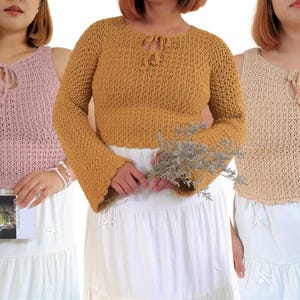 Puede incluir: Tres tops de ganchillo en diferentes colores: rosa claro, amarillo mostaza y beige. Los tops tienen un detalle de lazo en el escote. El top amarillo mostaza tiene mangas largas con puños acampanados. Las modelos llevan faldas blancas.