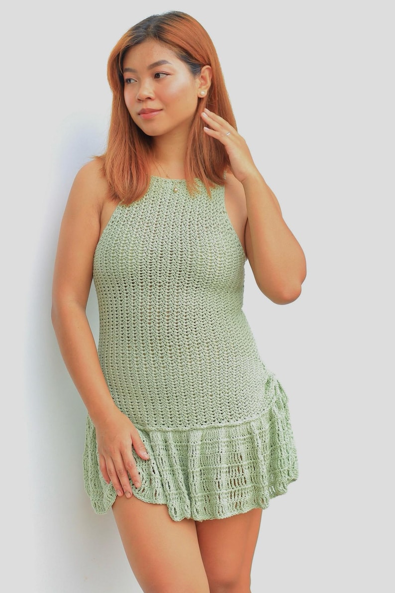 Puede incluir: Una mujer con un vestido de crochet verde salvia con un dobladillo con volantes.