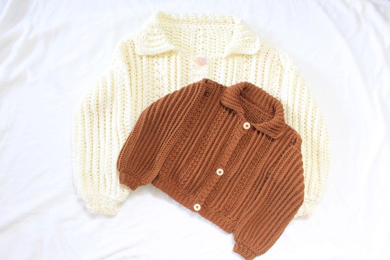 May include: Two crocheted cardigans, one in white and one in brown, with button closures.