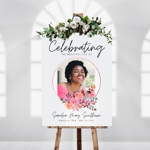 May include: A white memorial sign with a floral wreath at the top. A photo of a woman is in a circle with a pink floral design. The text reads "Celebrating the beautiful life of Sandra May Southern March 4, 1988 - May 15, 2021".