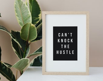Könnte beinhalten: Ein gerahmter Druck mit schwarzem Hintergrund und weißem Text, der "CAN'T KNOCK THE HUSTLE" lautet. Der Rahmen ist aus hellem Holz und der Druck liegt auf einer weißen Oberfläche.