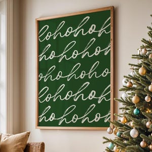 Puede incluir: Una escena interior festiva con un árbol de Navidad decorado con adornos dorados, plateados y turquesas. Una pizarra verde enmarcada con las palabras "hohoho" en escritura blanca cuelga de la pared. También se ve un árbol más pequeño y un sofá.