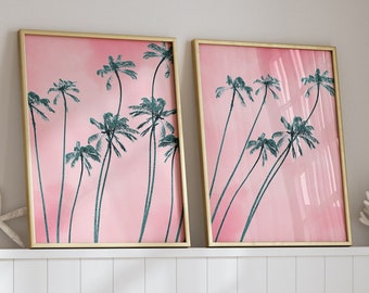 May include: Two framed art prints with gold frames, featuring teal palm trees against a pink background. The prints are displayed above a white shelf with a gold lamp, starfish, and a straw hat. The room has a coastal theme.