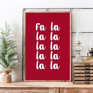 以下が含まれることがあります： 「Fa la la la la la la la」と白文字で書かれた赤い印刷可能な壁の芸術プリントです。