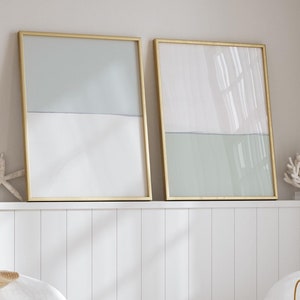 以下が含まれることがあります： 白い椅子が2つ、1つに麦わら帽子が置かれ、丸い木製のコーヒーテーブルが2つ、1つにガラスのランタンとビーズのガーランドが置かれ、薄い青と白の抽象画が額装されたものが2つある。