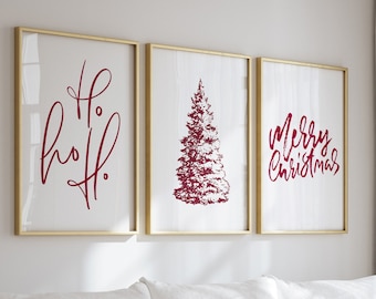 May include: A white sectional sofa with a white throw blanket on the armrest sits in a living room with a wooden coffee table and two gold lanterns. Three framed prints with gold frames hang on the wall behind the sofa. The prints feature a Christmas tree, the words "Ho, Ho, Ho!" and the words "Merry Christmas".