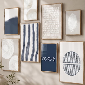 Puede incluir: Un conjunto de ocho láminas enmarcadas para pared con diseños abstractos en azul marino y blanco, que incluyen rayas verticales, líneas onduladas, patrones circulares y un motivo de hoja, en marcos de madera clara dispuestos en conjunto.