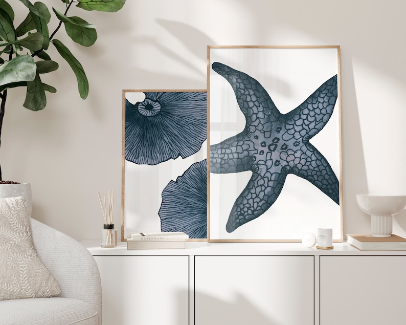 Op de afbeelding: Twee ingelijste prints met een witte achtergrond en blauwe illustraties. De ene print toont een zeester en de andere een gestileerde paddenstoel.