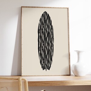 Puede incluir: Impresi&oacute;n de arte abstracto en blanco y negro de una tabla de surf con un patr&oacute;n ondulado. La impresi&oacute;n est&aacute; enmarcada en un marco de madera claro y est&aacute; colgada en una pared blanca.