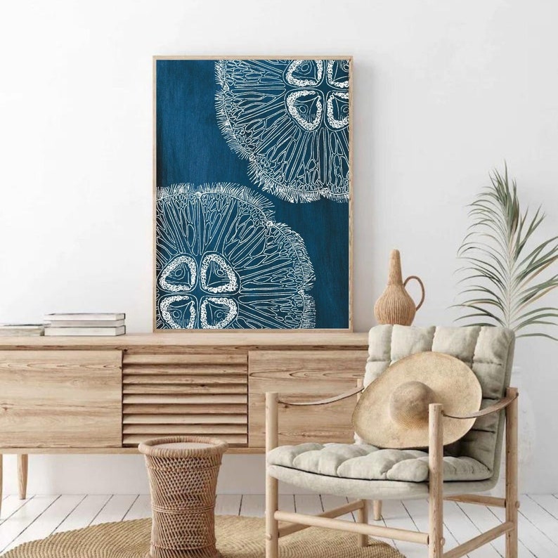 Puede incluir: Una impresi&oacute;n enmarcada con fondo azul y dos ilustraciones estilizadas blancas de un erizo de mar. La impresi&oacute;n est&aacute; colgada en una pared blanca sobre un armario de madera.