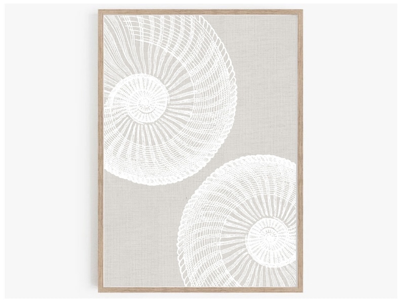K&ouml;nnte beinhalten: Ein gerahmter Druck mit beigefarbenem Hintergrund und zwei wei&szlig;en, geometrischen, kreisf&ouml;rmigen Designs. Die Designs erinnern an einen geflochtenen Korb oder eine Muschel.