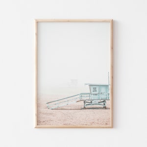 May include: A light blue lifeguard stand with a wooden ramp leading up to it. The stand is on a sandy beach with a hazy sky in the background.