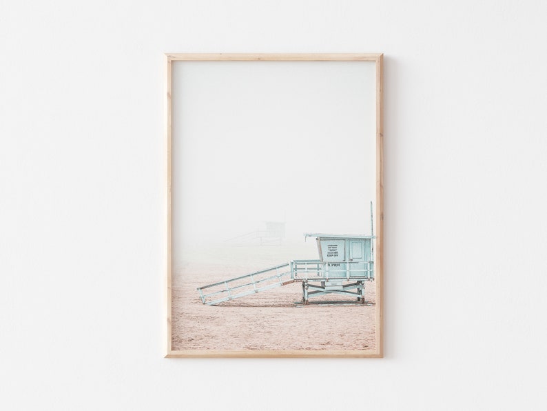 May include: A light blue lifeguard stand with a wooden ramp leading up to it. The stand is on a sandy beach with a hazy sky in the background.