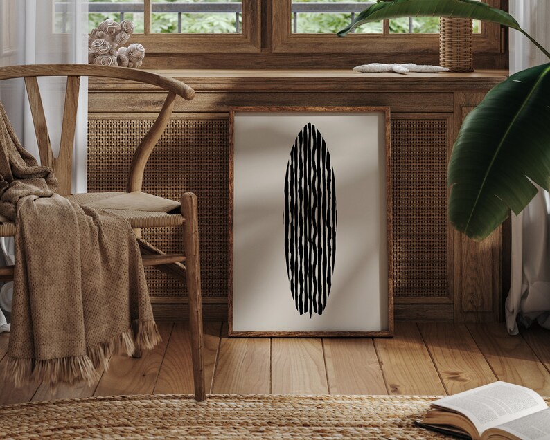 Puede incluir: Una impresi&oacute;n abstracta en blanco y negro de una tabla de surf colgada en un marco de madera en una pared. El marco est&aacute; en una pared con un panel de rat&aacute;n tejido y una silla de madera con una manta de lana marr&oacute;n.