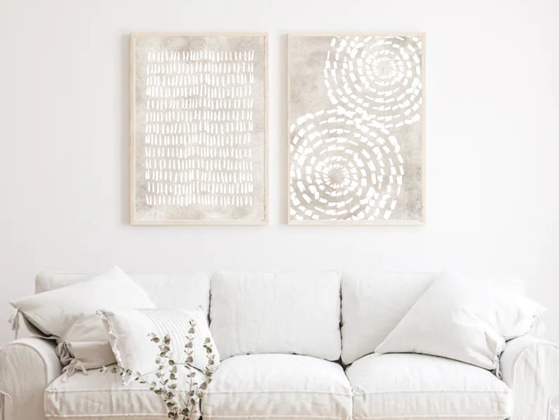 Puede incluir: Dos impresiones de arte abstracto enmarcadas con un esquema de color blanco y gris. La impresi&oacute;n de la izquierda presenta un patr&oacute;n de l&iacute;neas blancas sobre un fondo gris. La impresi&oacute;n de la derecha presenta dos patrones circulares blancos sobre un fondo gris.